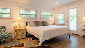 A bedroom with a large bed, two bedside tables with lamps, a chair, and a window with blinds. - Casa la Cala - Serious Fun + Luxury Relaxation! (Safety Harbor)