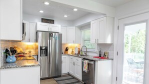 A modern kitchen with white cabinets, stainless steel appliances, and a granite countertop. - Casa la Cala - Serious Fun + Luxury Relaxation! (Safety Harbor)