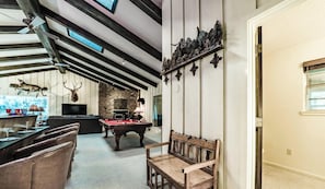 Une pièce avec une table de billard, une cheminée et un mur en pierre.