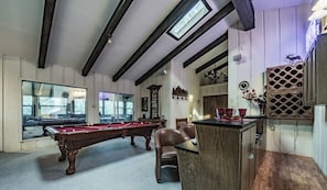 Une salle de billard équipée de deux tables de billard, d’un buffet en bois et d’une chaise.