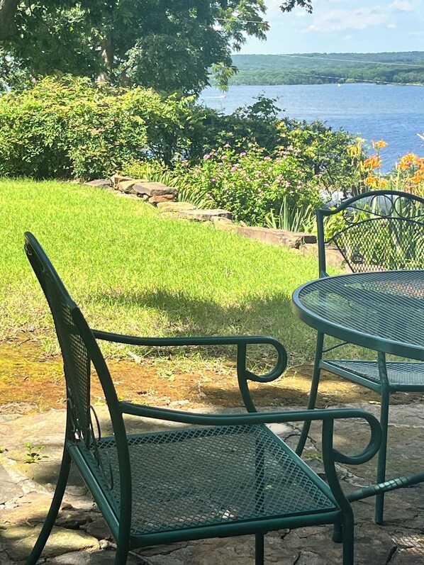 A patio with a table and chairs, a grassy area, and a view of a body of water.