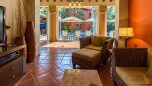 A lobby with a tiled floor, wicker furniture, a television, and a view of an outdoor pool area.