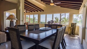 A dining area with a large table, chairs, and a ceiling fan.