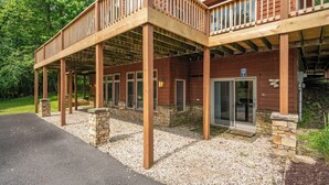 A two-story wooden building with a covered patio area, stone pillars, and a gravel driveway. - Cozy Chalet w/ Views, Fireplaces & Fun (McHenry)