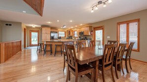 A spacious kitchen with wooden cabinets, a central island, and a dining area with a large wooden table and chairs. - Cozy Chalet w/ Views, Fireplaces & Fun (McHenry)