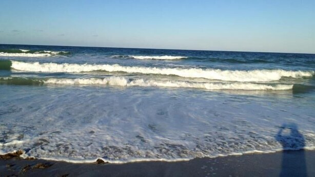 Ein Strand mit Wellen und blauem Himmel.