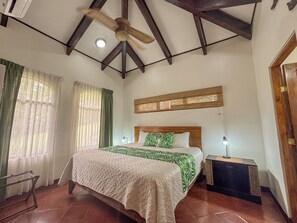 A bedroom with a bed, a nightstand, a ceiling fan, and a window with curtains. - Los Sueños Luxury Villa, Private Infinity Pool & Golf Views (Los Suenos)