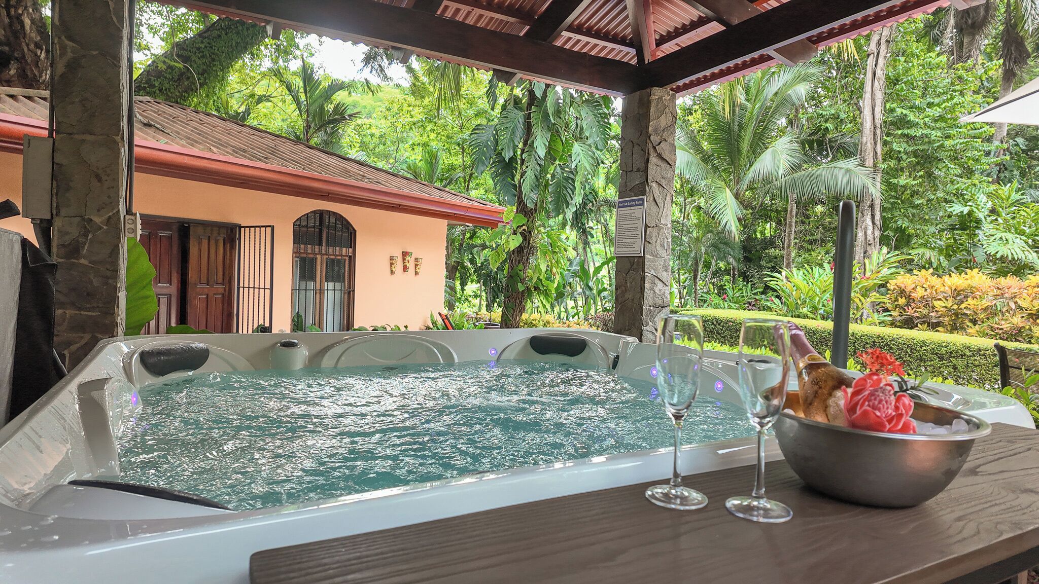 A hot tub with a view of a house and lush greenery.