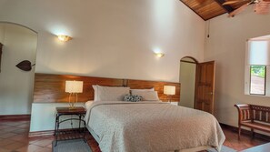 Une chambre à coucher avec un lit, des lampes de chevet, une tête de lit en bois, un miroir et une fenêtre.