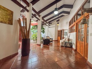 Una habitación amplia con suelo de baldosas, un ventanal grande y una puerta de madera.