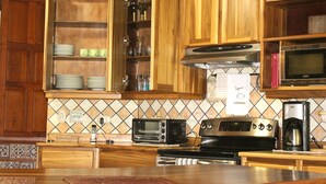 Une cuisine avec des meubles de rangement en bois, un four à micro-ondes, un grille-pain et une machine à café.