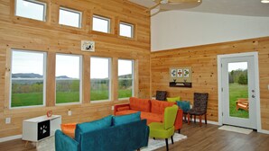 A spacious room with large windows, a ceiling fan, and a view of the outdoors. - Super Fun Shipping Container Home! Spacious and Stylish! (Sumner)