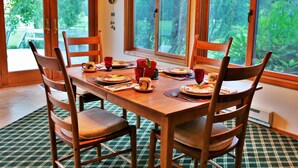 Une table à manger dressée pour quatre personnes, avec des chaises, des assiettes, des tasses et un vase.