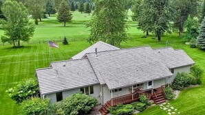 Une maison avec un toit en pente, entourée d’une pelouse bien entretenue et d’arbres.