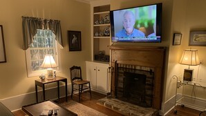 A living room with a fireplace, television, and seating area. - QUAINT COTTAGE IN HISTORIC OLD POINT   Beaufort, S.C. (Beaufort)