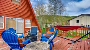 A wooden deck with blue chairs, a fire pit, and a hammock. - Mountain Views, Hot Tub, Incredible Location! Dog Friendly! 
BCA-47331 (Dillon)