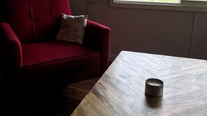 Ein rotes Sofa mit Kissen, ein Couchtisch aus Holz und ein Fenster mit Blick auf Grünflächen.