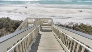 Une promenade en bois menant à une plage avec vue sur l’océan.