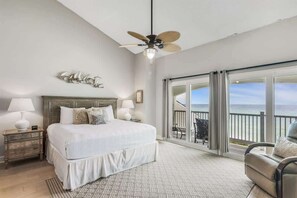 Quarto com cama, mesas de cabeceira, ventilador de teto e varanda com vista.