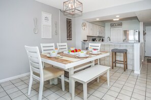 Une cuisine moderne avec des meubles blancs, une table à manger entourée de chaises blanches et un banc.