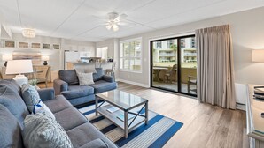 A modern living room with a sofa, coffee table, and a view of a balcony. - Beach-side, beautiful low-rise with uncrowded beach! (Destin)