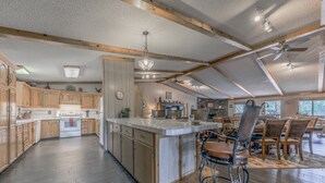 Une cuisine spacieuse dotée de meubles en bois, d’un îlot central et d’un coin repas avec des tabourets de bar.