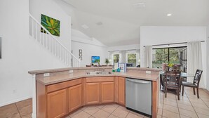 A modern kitchen with a wooden island, a dishwasher, and a dining area with a table and chairs. - 6 miles to Disney: Clean Family 4 Beds, 3.5 Bath, pool/hot tub, game room, grill (Kissimmee)
