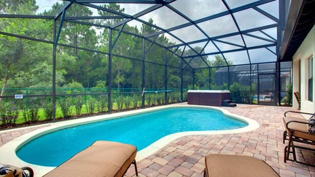 A covered swimming pool with a brick patio, lounge chairs, and a hot tub. - 6 miles to Disney: Clean Family 4 Beds, 3.5 Bath, pool/hot tub, game room, grill (Kissimmee)
