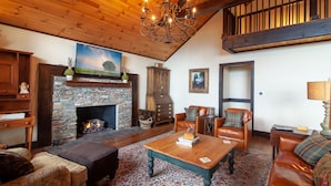 A cozy living room with a stone fireplace, leather furniture, and a wooden ceiling. - Large Mountain Home with Multi-Mile Views (Boone)