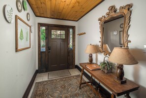 A hallway with a wooden door, a mirror, a table with lamps, and a rug. - Spacious Lodge with Stunning Views, Hot Tub, Game Room & Fireplaces | Minutes to Downtown Boone (Boone)