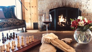 A cozy room with a fireplace, a chessboard, slippers, and a vase of flowers. - Historic Author's Lodge- Hot Tub as Featured in San Diego Magazine Walk to town. (Idyllwild)