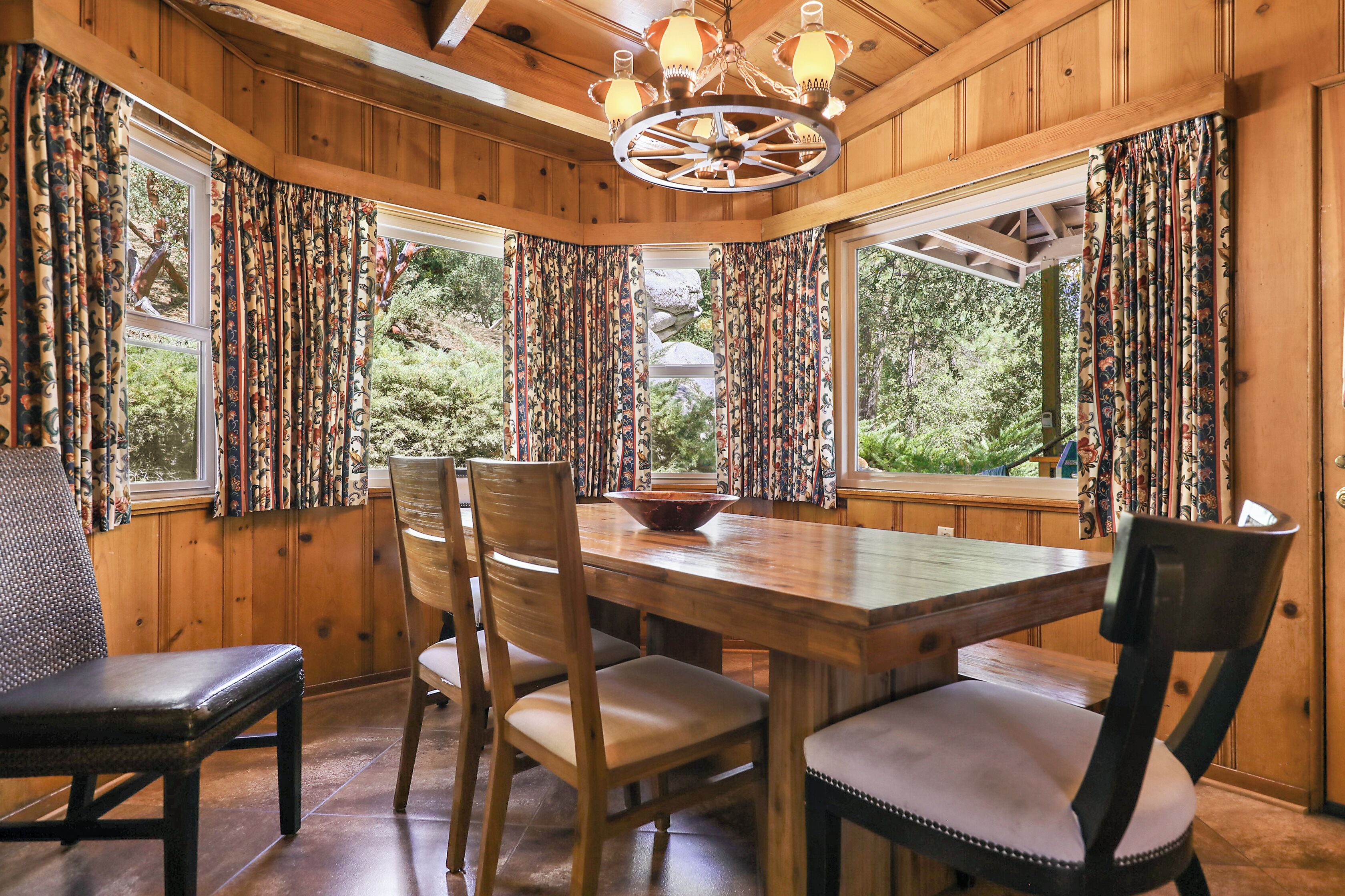 A wooden dining area with a large table, chairs, and a chandelier.