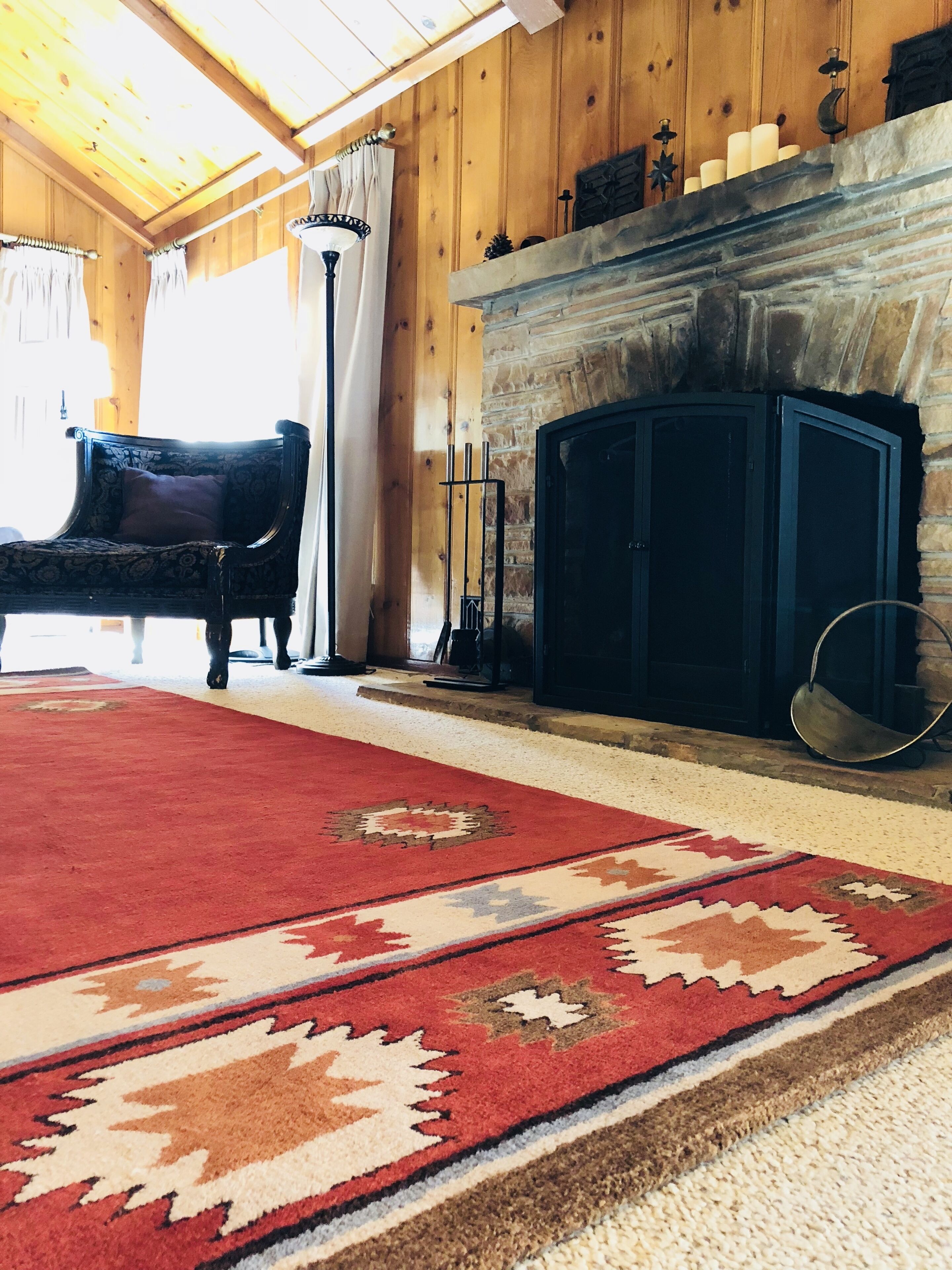 A cozy room with a fireplace, a red carpet, and a wooden ceiling.