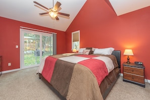 A bedroom with a bed, a nightstand, a ceiling fan, and a window with a view of the outdoors. - Split Lakefront Gem w/ Pool Table & Dock Slip (Oakland)