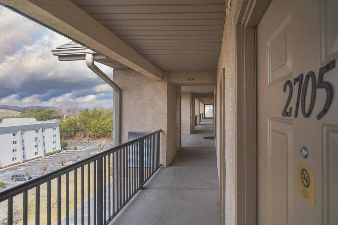 A corridor with a view of a parking lot and a building in the distance.