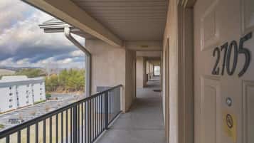 A corridor with a view of a parking lot and a building in the distance.