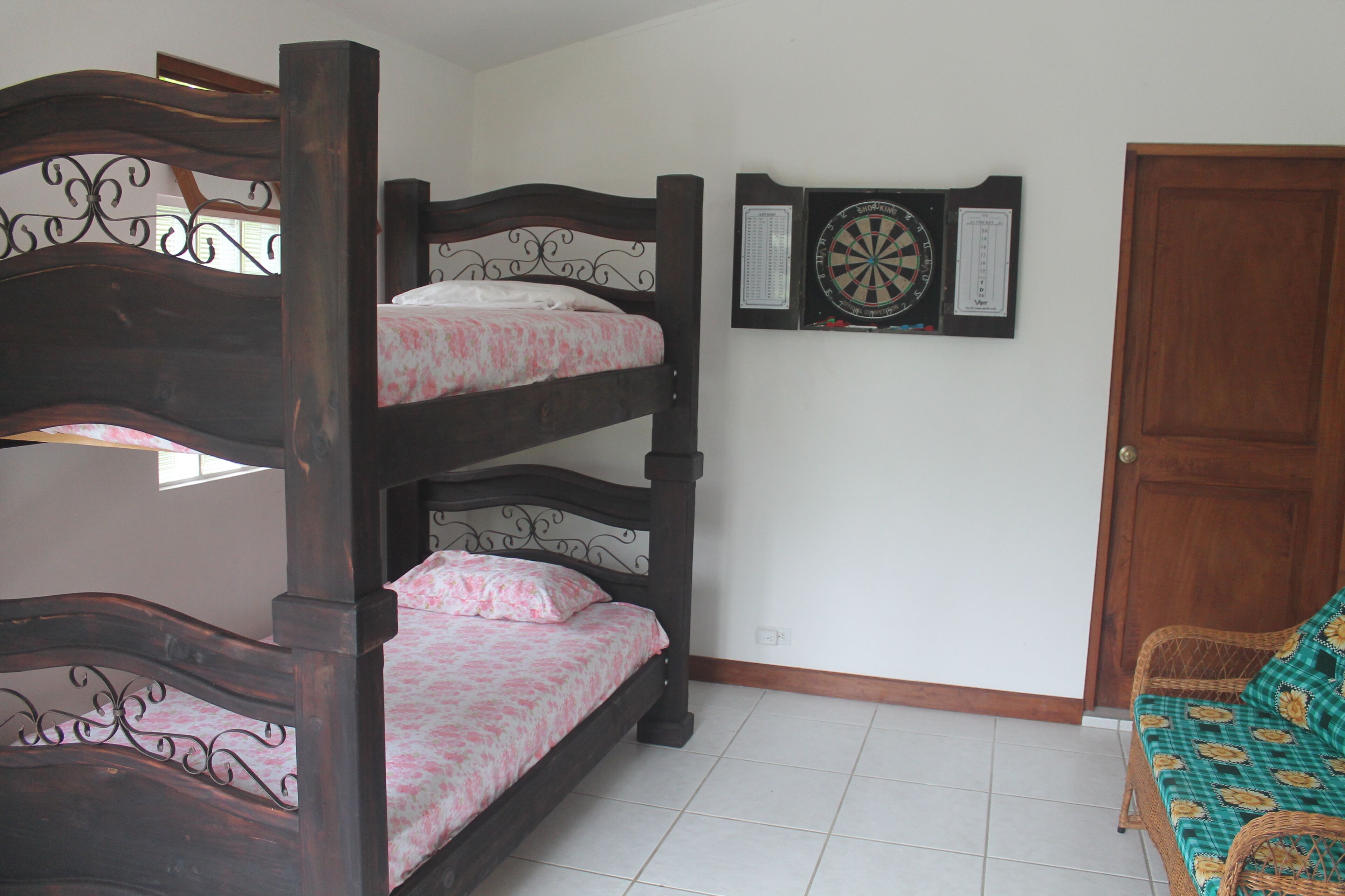 Una cama litera con ropa de cama estampada, un dardo y una puerta de madera.