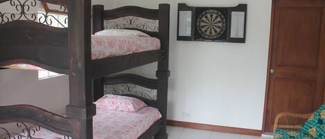 Una cama litera con ropa de cama estampada, un dardo y una puerta de madera.