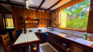 Una cocina con armarios de madera, una estufa a gas, un lavabo y una ventana con vistas al verdor.