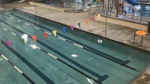 An indoor swimming pool with multiple lanes, a water slide, and a play area.