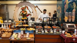 A buffet with various food items, a chef preparing food, and a decorative archway. - Empires Hotel Paradip (Kujang)