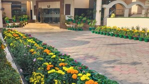 A hotel entrance with a paved walkway, potted plants, and a building facade. - Empires Hotel Paradip (Kujang)