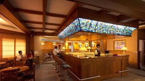 A bar area with a wooden counter, stools, and a stained glass window above. - Empires Hotel Paradip (Kujang)