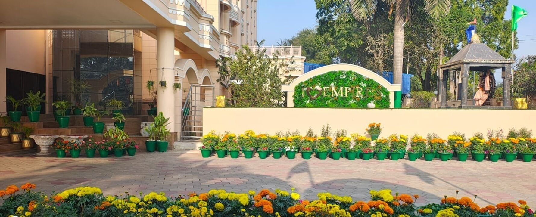 A hotel entrance with a sign, potted plants, and a well-maintained flower bed.
