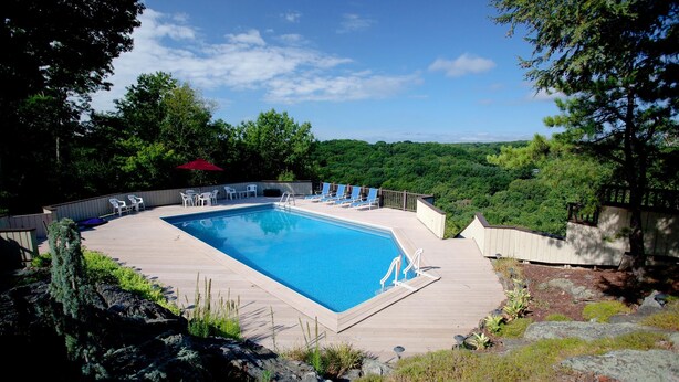 A rectangular swimming pool with a wooden deck, surrounded by lounge chairs and a red umbrella. - 1ST FLR APT Your Private Resort, now FAMILY-ized: 1 BR + LR suitable for 2 kids  (Shelton)