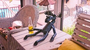 A wicker chair, a wooden table with a bottle, and a metal sculpture. - 1ST FLR APT Your Private Resort, now FAMILY-ized: 1 BR + LR suitable for 2 kids  (Shelton)