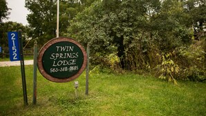 A sign for Twin Springs Lodge with a contact number. - Private Lodge Near Trails & River • Sauna • Sleeps 8 (Decorah)