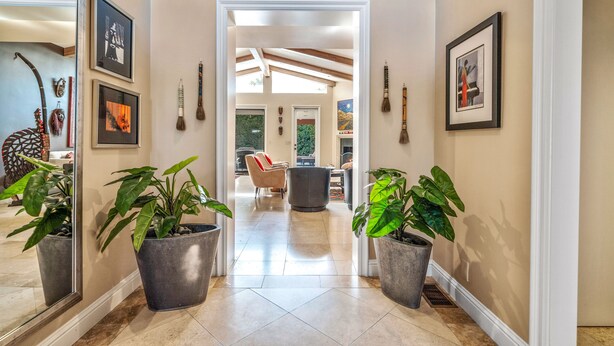 A hallway with large potted plants, framed artwork, and a view into a dining area. -  Gorgeous, Spacious Villa in Upscale Canyon Estates - Pool/Spa - Dog OK  (Palm Springs)