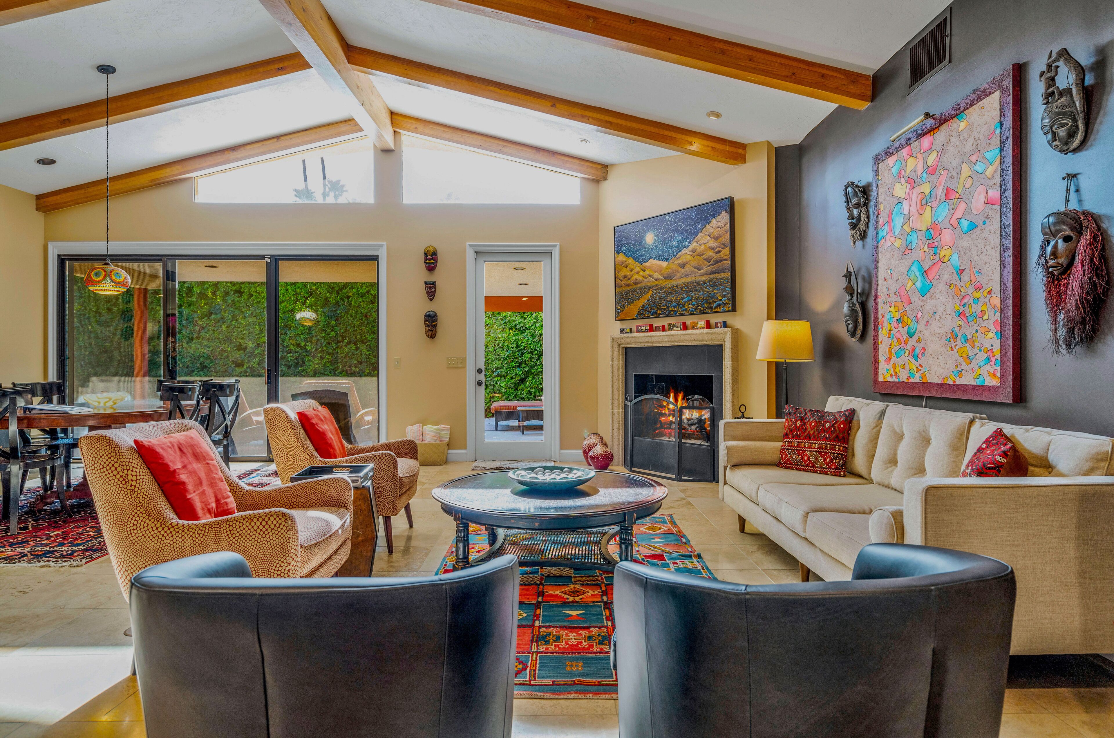 A spacious living room with a fireplace, comfortable seating, and a large window overlooking greenery.