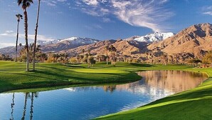 A golf course with a pond, palm trees, and mountains in the background. -  Gorgeous, Spacious Villa in Upscale Canyon Estates - Pool/Spa - Dog OK  (Palm Springs)